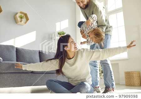 Mother, father and little daughter at home having fun playing fooling around and laughing. Mother, father and little daughter at home having fun playing fooling around and laughing. 97909398