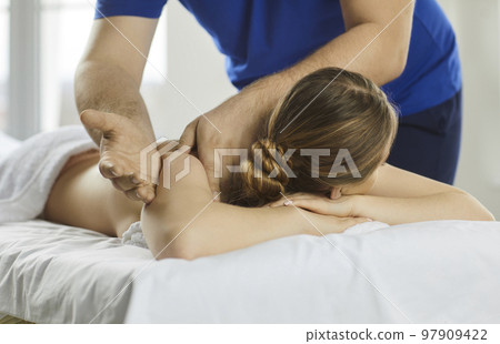 Young woman enjoying osteopathic back and shoulder massage in therapeutic massage parlor. 97909422