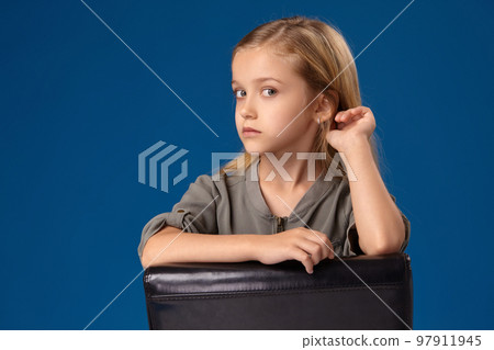 Little girl with gray eyes and blond hair sits on a chair Little girl with gray eyes and blond hair sits on a chair 97911945