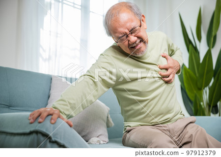 Senior man bad pain hand touching chest having heart attack, Asian older man have congenital disease suffering from heartache alone at home his heart aches, Old age retirement health problems diseases 97912379