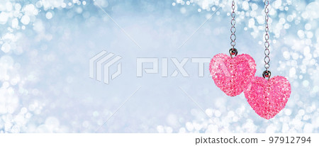 Two Pink red sparkling crystals heart pendants, valentine day greeting card. Bokeh blue abstract background. Valentines Day card or winter wedding wide web banner. Couple love Two Pink red sparkling crystals heart pendants, valentine day greeting card. Bokeh blue abstract background. Valentines Day card or winter wedding wide web banner. Couple love 97912794
