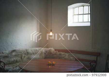 Single light bulb hanging over a wooden table 97912900