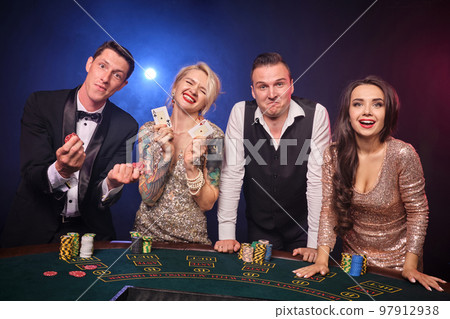 Group of a stylish rich friends are playing poker at casino. 97912938