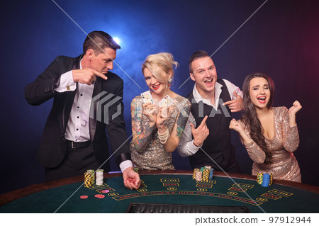 Group of a stylish rich friends are playing poker at casino. 97912944