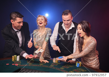Group of a stylish rich friends are playing poker at casino. 97912957