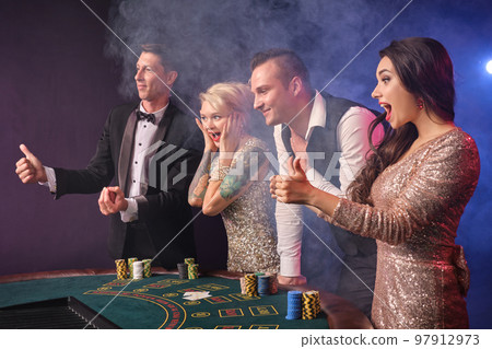 Group of a stylish rich friends are playing poker at casino. 97912973