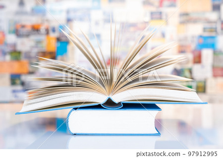 Open book on table in front of colorful soft background  97912995