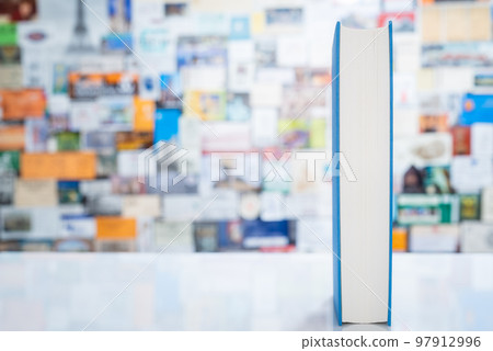Single book standing on table in front of colorful blurred background Single book standing on table in front of colorful blurred background 97912996