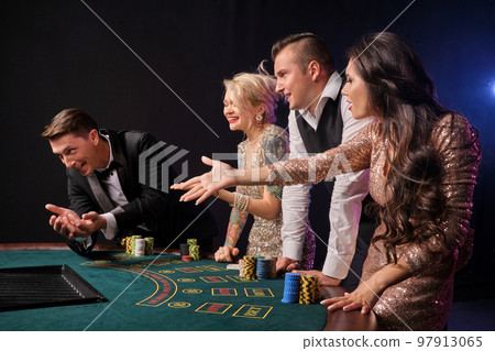 Group of a stylish rich friends are playing poker at casino. 97913065