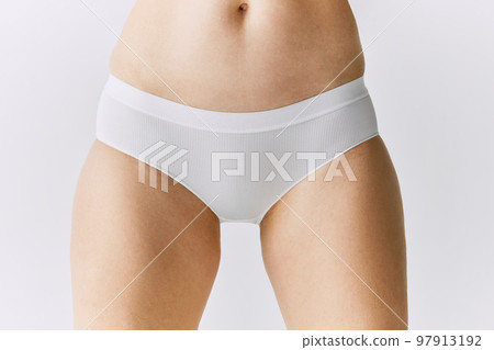 Cropped image of female body, belly, buttocks in underwear posing over grey studio background. Front view Cropped image of female body, belly, buttocks in underwear posing over grey studio background. Front view 97913192