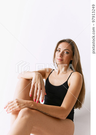 Sexy woman in black underwear sitting in the studio against grey