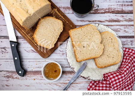 Aerial view of a homemade bread made with a bread machine, some slices and sweet on a table 97913595