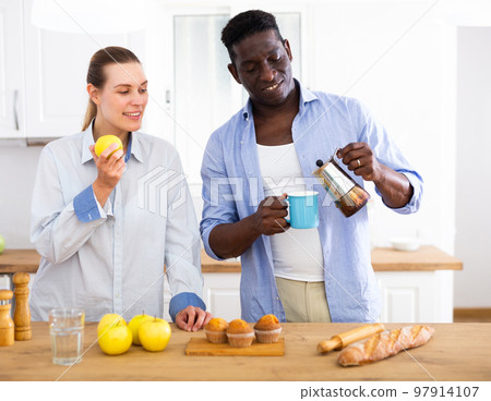 Positive couple having breakfast in kitchen at home Positive couple having breakfast in kitchen at home 97914107