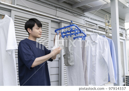 A young man hanging up the laundry A young man hanging up the laundry 97914337