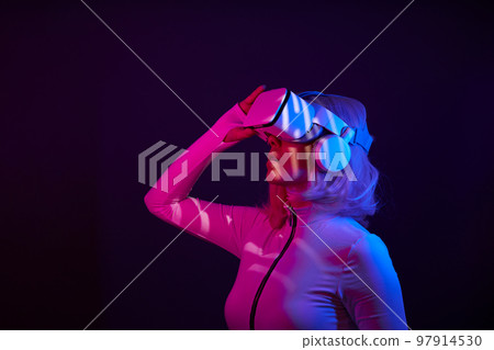 Woman in virtual reality goggle in neon colors. Woman in virtual reality goggle in neon colors. 97914530