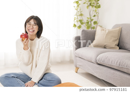 坐在客廳裡拿著蘋果的女人 97915181