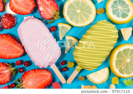 Two ice creams on a sticks - strawberry and lemon on a blue background. Summer fruit desserts. Two ice creams on a sticks - strawberry and lemon on a blue background. Summer fruit desserts. 97917110