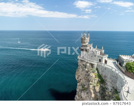 Crimea Swallow's Nest Castle on the rock over the Black Sea. It is a tourist attraction of Crimea. Amazing aerial view of the Crimea coast with the castle above abyss on sunny day. Crimea Swallow's Nest Castle on the rock over the Black Sea. It is a tourist attraction of Crimea. Amazing aerial view of the Crimea coast with the castle above abyss on sunny day. 97917643