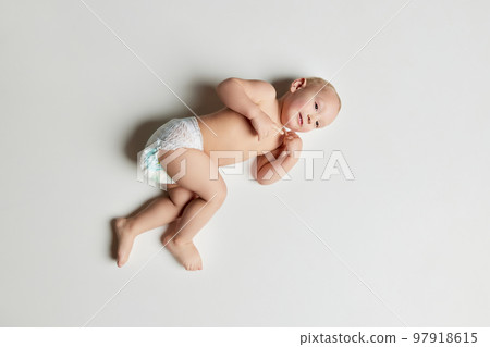 Aerial view of cute infant, little child baby toddler wearing nappy lying on floor with happy facial expression over light background. Happy childhood, family Aerial view of cute infant, little child baby toddler wearing nappy lying on floor with happy facial expression over light background. Happy childhood, family 97918615
