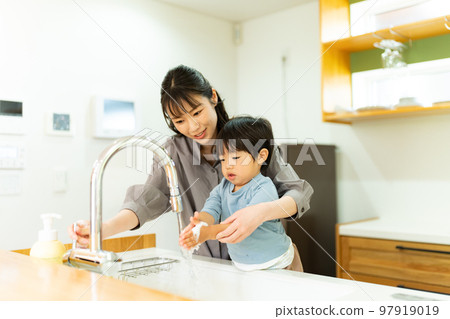 A mother helping a 2-year-old boy to wash his hands 97919019
