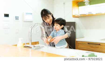 A mother helping a 2-year-old boy to wash his hands 97919021