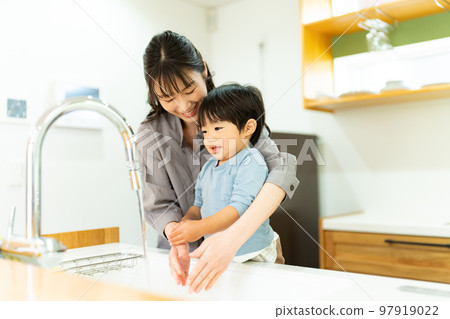 A mother helping a 2-year-old boy to wash his hands 97919022