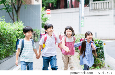 Elementary school students holding hands and walking on the sidewalk 97919395
