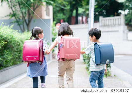 Elementary school students holding hands and walking on the sidewalk 97919397