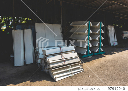 Empty old metal book or magazines shelves. Old bookshelves that are no longer in use due to the end of the new generations reading era have been abandoned and no longer matter in front of the old shed 97919940
