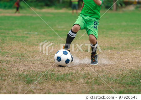Football soccer children training class. Kindergarten school kids playing football in a field. Group of boys running and kicking soccer on sports grass pitch. Children in sportswear on football match. 97920543