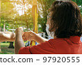 Female teacher teaches student to aim at goal. An archer teaching young man archery on field. Instructor teaching man to use bow and arrow on archery training. Archery course. Selective focus on hand. 97920555