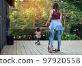 Asian woman enjoy playing and riding modern extreme stunt kick scooter without using any safety gear in home. Active sport lifestyle of young female in nature. Happy woman ride scooter without helmet. 97920558