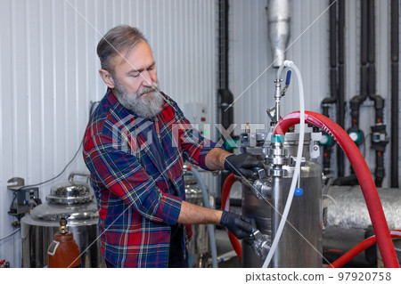 Man in plaid shirt working at the brewery and looking contented Man in plaid shirt working at the brewery and looking contented 97920758