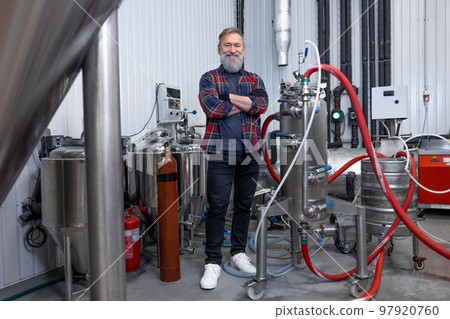 Man in plaid shirt working at the brewery and looking contented Man in plaid shirt working at the brewery and looking contented 97920760