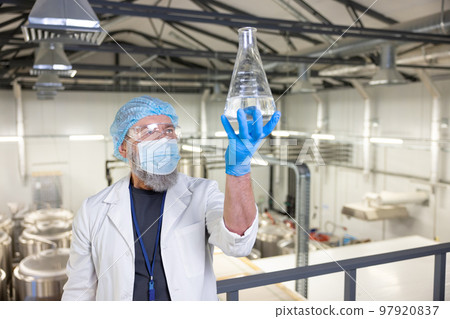 Brewery technologist examining the contents of a graduated vessel Brewery technologist examining the contents of a graduated vessel 97920837