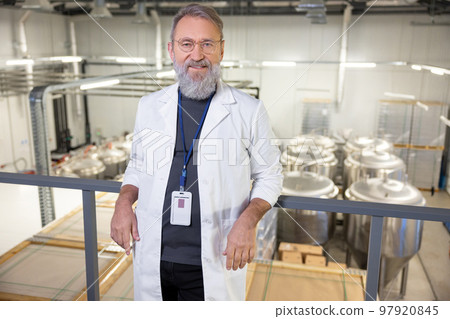 Joyous technologist posing for the camera against big metal tanks 97920845