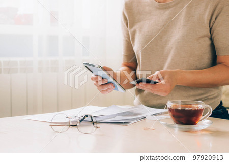 Woman holds phone in her hands for paying bills, receipts of financial checks, budget planning 97920913