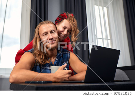 Image of successful young couple man and woman working on laptops together while sitting at table at home. Happy spouses in love have success in new project with happiness and good emotion Image of successful young couple man and woman working on laptops together while sitting at table at home. Happy spouses in love have success in new project with happiness and good emotion 97921055