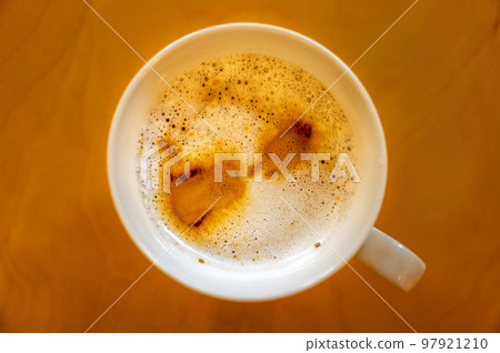 Cup of coffee on a table seen from above. Cafe latte macchiato with coffee marks on the top of the drink and bubbles in the foam. 97921210