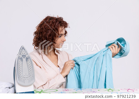 Before ironing, the girl carefully inspects the shirts. 97921239