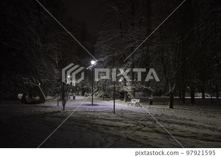 Illuminated public park at night. Pathway through the snow public park. Illuminated public park at night. Pathway through the snow public park. 97921595