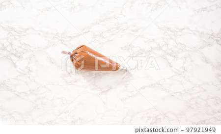 Flat lay. Step by step. Chocolate ganache frosting in a piping bag with a metal tip. Flat lay. Step by step. Chocolate ganache frosting in a piping bag with a metal tip. 97921949
