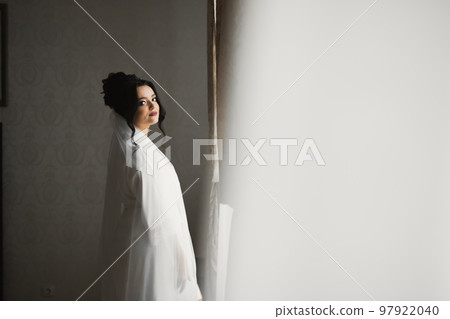 Beautiful bride wearing fashion wedding dress with feathers with luxury delight make-up and hairstyle, studio indoor photo shoot Beautiful bride wearing fashion wedding dress with feathers with luxury delight make-up and hairstyle, studio indoor photo shoot 97922040