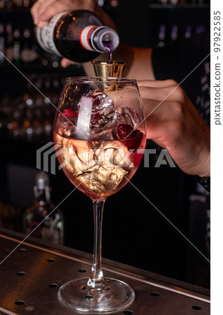 The process of preparing an alcoholic fiery cocktail drink. A male bartender pours alcohol into a glass. The process of preparing an alcoholic fiery cocktail drink. A male bartender pours alcohol into a glass. 97922585