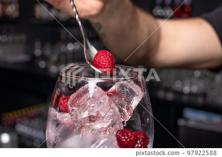 Ice cubes and raspberries in a glass. The process of nailing the cocktail. 97922588