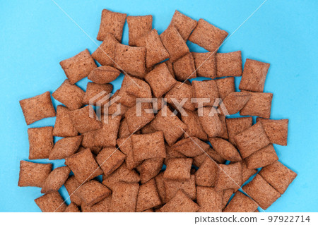 Sweet breakfast cereal dry - chocolate pads made of cereals on a blue background, viewed from above. 97922714