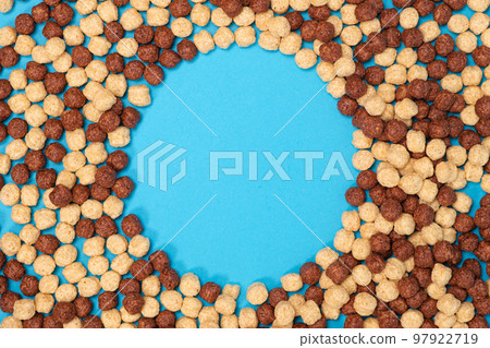 Breakfast cereal in the form of cocoa balls on a blue background, a place for text in the center Breakfast cereal in the form of cocoa balls on a blue background, a place for text in the center 97922719