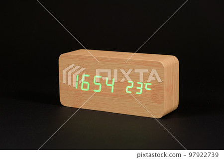 Electronic digital wooden clock with thermometer on a black background close-up. 97922739