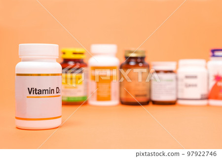 Vitamin D in a white jar with other dietary supplements on an orange background Vitamin D in a white jar with other dietary supplements on an orange background 97922746