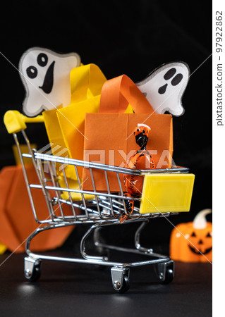 A small cart with bags, gifts on the black background of pumpkins. Halloween Sale 97922862